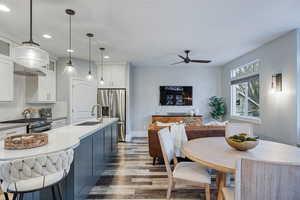 Two tone kitchen featuring light wood-style floors, decorative backsplash, stainless steel appliances, pendant lighting, and glass insert cabinets