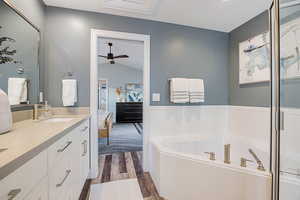 Ensuite bathroom with double vanity, dark wood finished floors, a bath, and ceiling fan