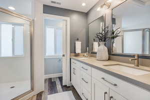 Full bathroom featuring a shower stall, double vanity, dark wood-style floors, and recessed lighting