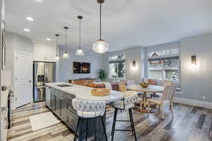 Kitchen with stainless steel appliances, a center island with sink, two tone cabinets, a kitchen breakfast bar, and open floor plan