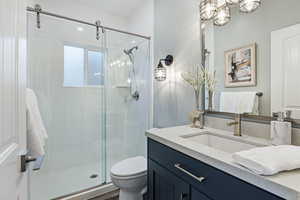 Bathroom with vanity, a stall shower, and hanging lights