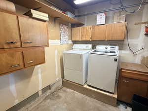 Laundry room featuring cabinet space, concrete flooring, and washing machine and clothes dryer