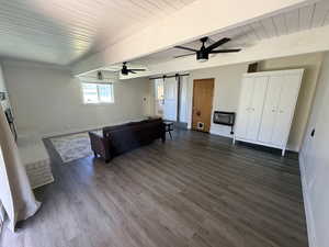 Living area featuring a barn door, a fireplace, dark wood-type flooring, ceiling fan, and heating unit
