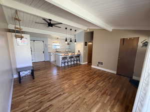 Living area with dark wood finished floors, ceiling fan, and lofted ceiling with beams