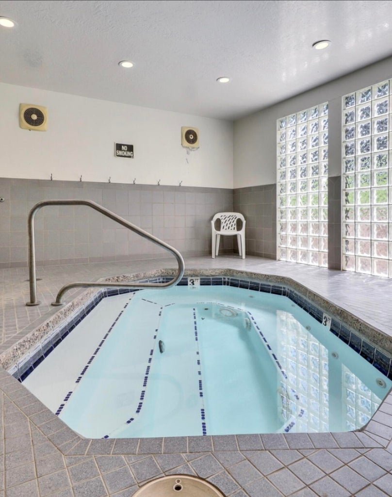 View of swimming pool with a hot tub