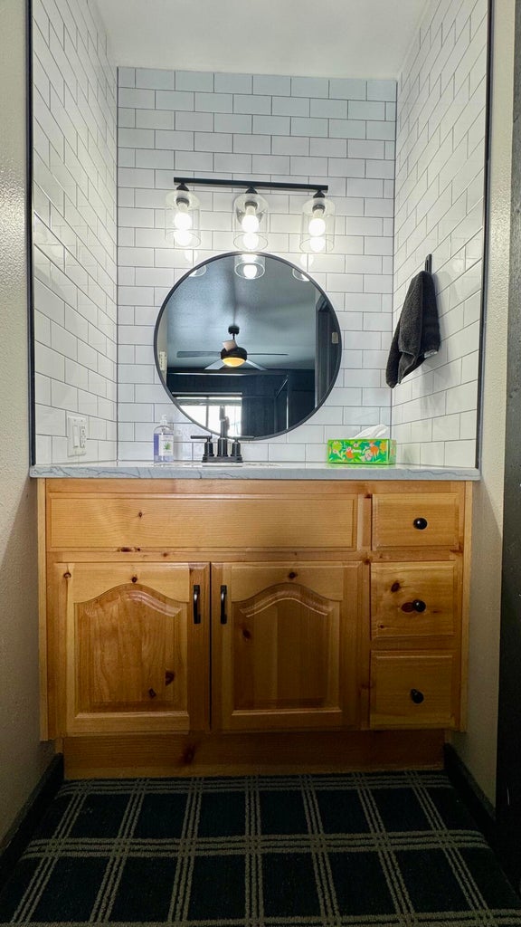 Bathroom featuring vanity, a textured wall, and backsplash