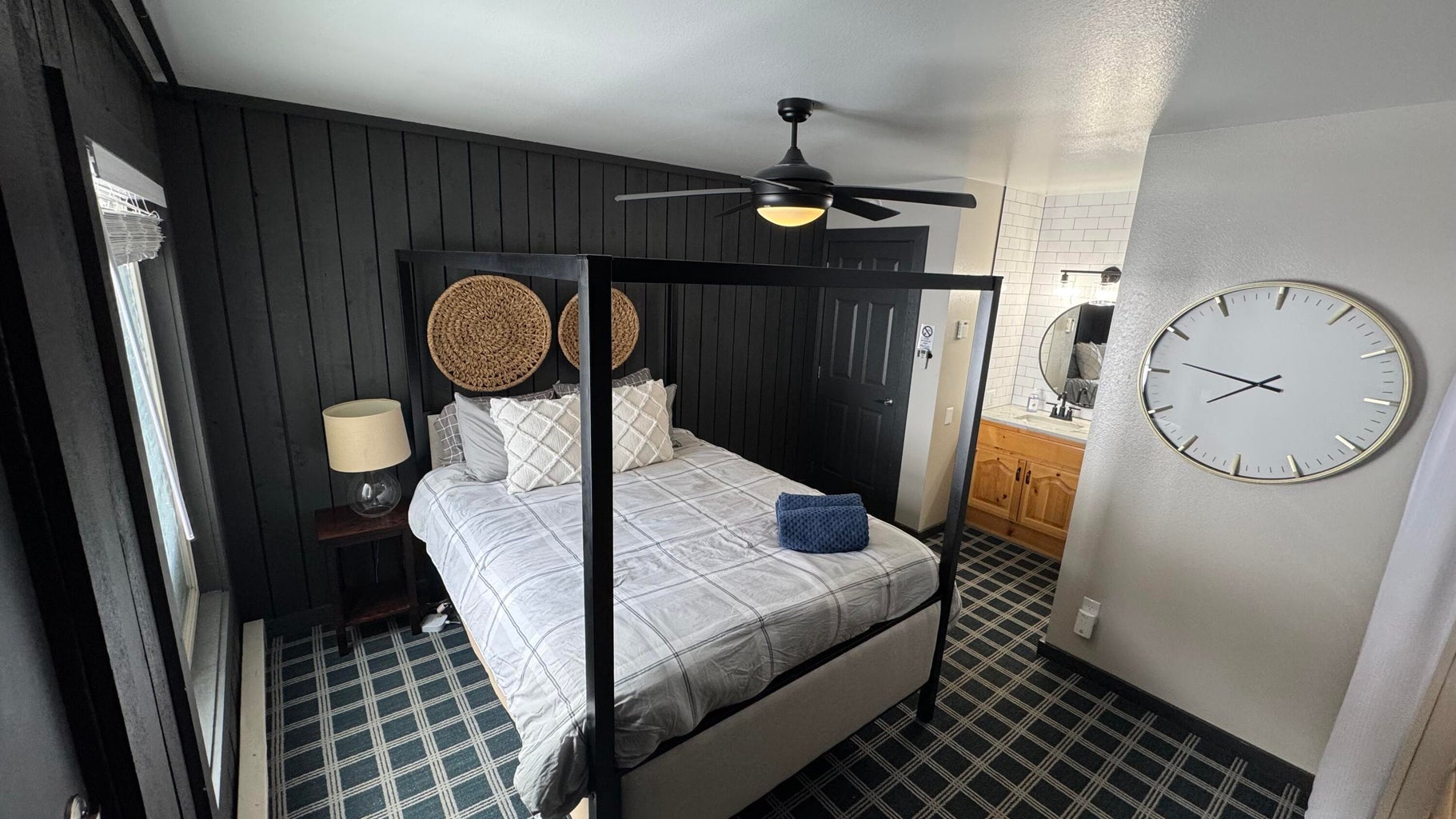 Bedroom featuring ensuite bathroom, dark colored carpet, ceiling fan, and wood walls