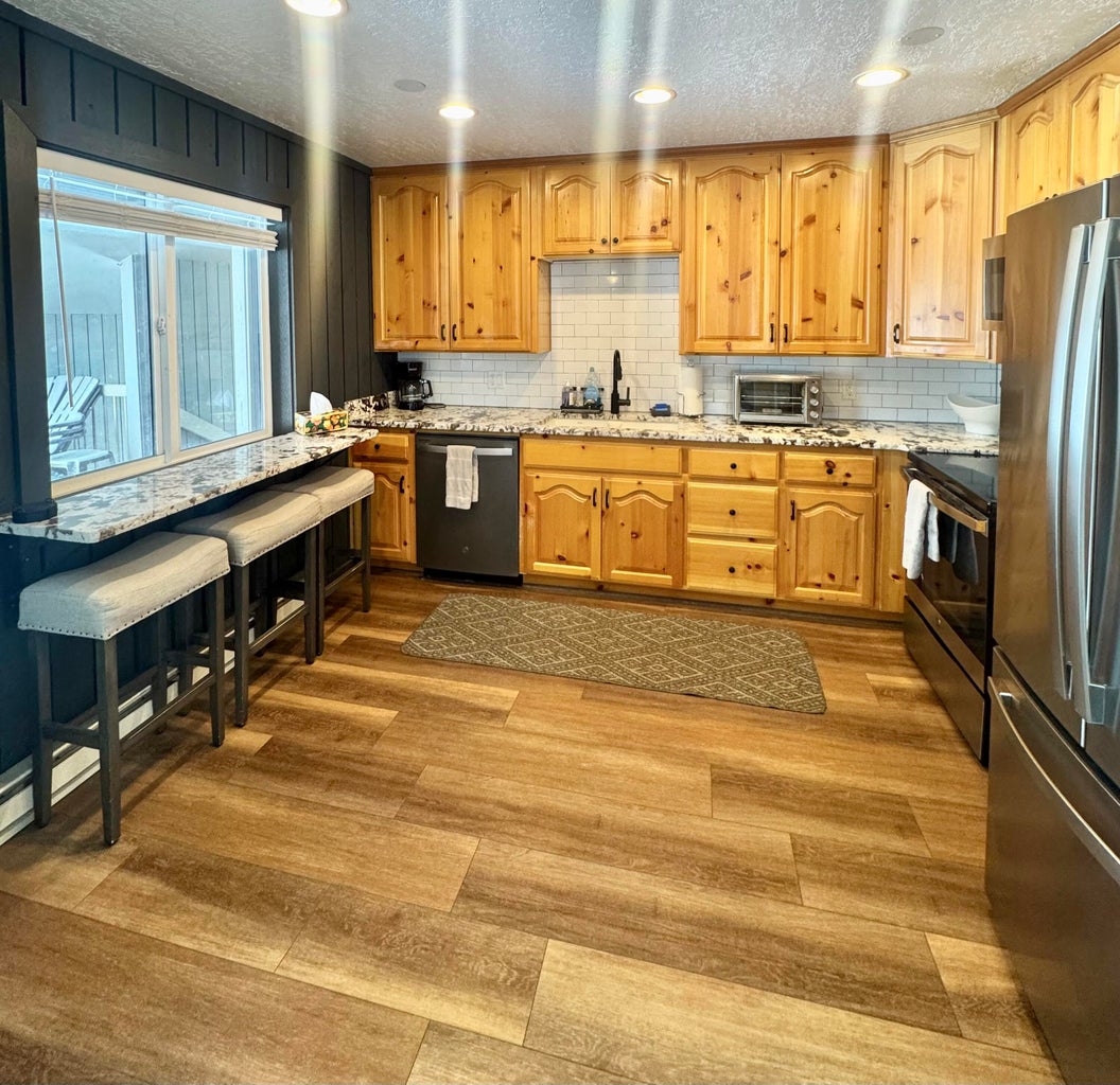 Kitchen featuring a textured ceiling, light stone countertops, stainless steel appliances, light wood finished floors, and recessed lighting