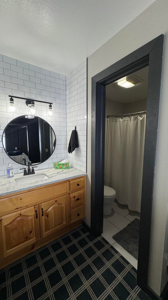 Bathroom featuring a shower with shower curtain, tasteful backsplash, vanity, and a textured ceiling