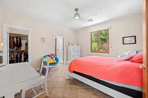 Bedroom featuring a spacious closet, light tile patterned floors, and ceiling fan