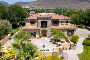 Mediterranean / spanish-style home with stone siding, a mountain view, stucco siding, a tiled roof, and driveway