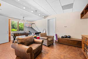 Living room with a drop ceiling, rail lighting, and dark tile patterned flooring