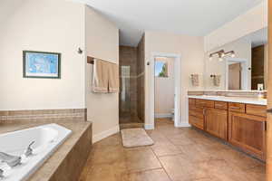 Bathroom with vanity, a tile shower, a garden tub, and light tile patterned floors