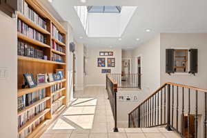 Hallway with light tile patterned floors, a skylight, and recessed lighting