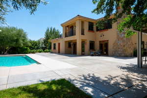 Back of house with a balcony, a tiled roof, stucco siding, an outdoor pool, and outdoor dining area