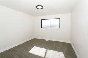 Spare room featuring baseboards and carpet floors