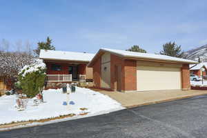 View of front of house featuring covered porch, a garage, and brick siding