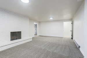 Unfurnished living room with carpet floors, baseboard heating, and a fireplace