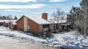 Snow covered house with a chimney and brick siding