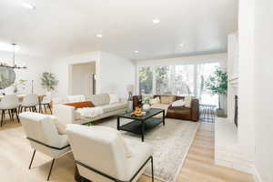 Living area featuring light wood-type flooring, a brick fireplace, and hanging lights