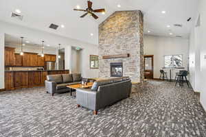 Living room featuring a fireplace, dark carpet, ceiling fan, lofted ceiling, and recessed lighting