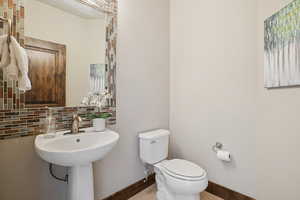 Half bathroom featuring tasteful backsplash and toilet