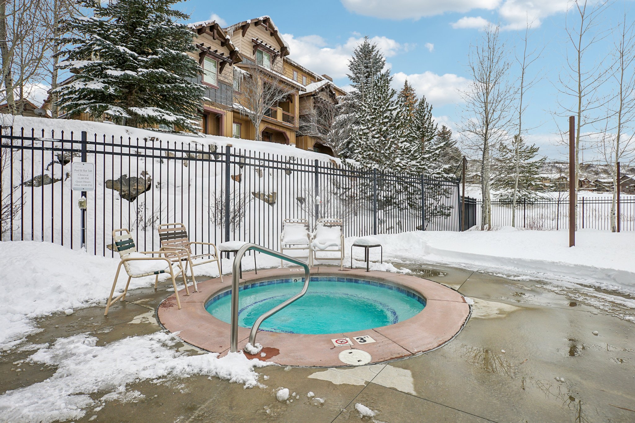 Snow covered pool with a community hot tub and a patio