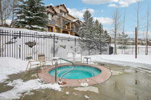 Snow covered pool with a community hot tub and a patio