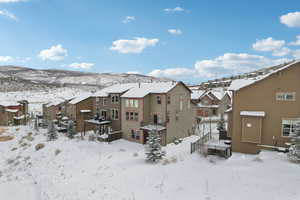 Snow covered rear of property with a wooden deck and a residential view