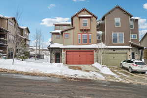 View of front of property featuring stone siding, a garage, and driveway