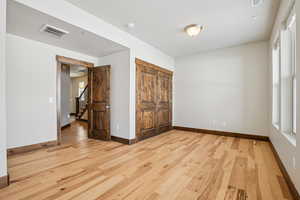 Unfurnished bedroom featuring light wood-type flooring and a closet