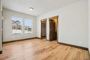 Unfurnished bedroom featuring a walk in closet and light wood finished floors