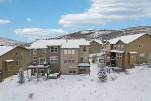 Snow covered rear of property featuring a mountain view and a patio area