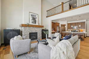 Living area featuring light wood-type flooring, a fireplace, a high ceiling, and recessed lighting