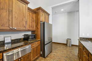 Kitchen with a warming drawer, freestanding refrigerator, wood finish cabinets, black microwave, and recessed lighting