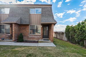 View of front of home with brick siding, roof with shingles, and board and batten siding