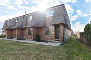 Rear view of property with brick siding, mansard roof, board and batten siding, and a shingled roof