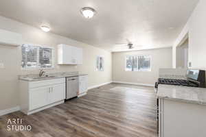 Kitchen featuring light stone counters, white cabinetry, stainless steel appliances, dark wood-style floors, and a textured ceiling