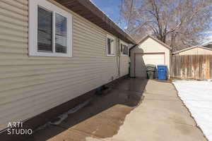 View of side of property featuring a garage, concrete driveway, and an outbuilding