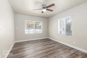 Empty room featuring dark wood-style floors, healthy amount of natural light, and ceiling fan