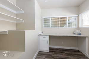 Unfurnished office featuring built in desk and dark wood finished floors