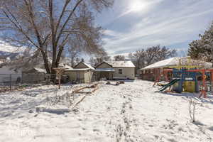 Yard covered in snow featuring a playground