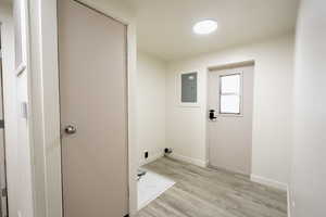 Laundry area with light wood-style floors and electric panel