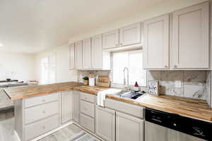 Kitchen with butcher block counters, a peninsula, dishwasher, light wood-style flooring, and open floor plan