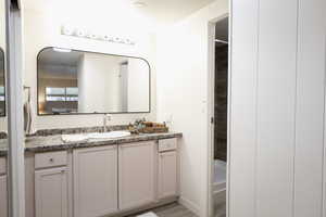 Ensuite bathroom with vanity, light wood finished floors, and a shower