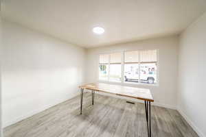 Unfurnished office featuring light wood-style flooring and baseboards