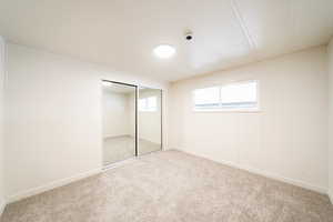Unfurnished bedroom with a closet, carpet flooring, and wooden walls