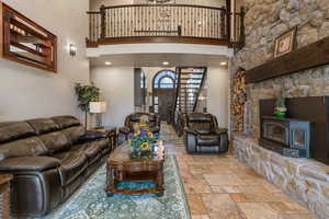 Living area featuring a high ceiling, stone tile floors, and a wood stove