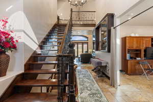 Staircase featuring a high ceiling, stone tile floors, and suspended lighting