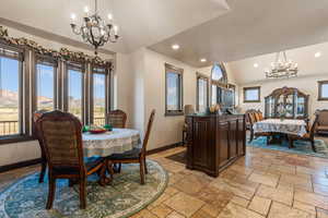 Dining space featuring suspended lighting, lofted ceiling, stone tile flooring, and a mountain view